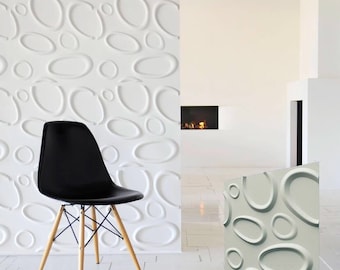 Puede incluir: Una silla negra con patas de madera se encuentra frente a una pared blanca con un patrón 3D de círculos superpuestos. La pared es un elemento de diseño moderno para un hogar u oficina.