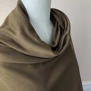 May include: A soft, olive green scarf draped over a mannequin. The scarf is made of a smooth, lightweight fabric.