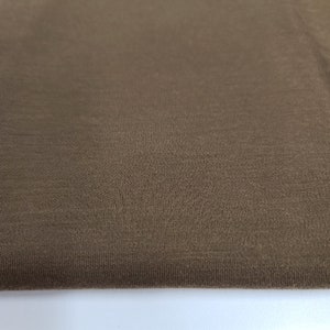 May include: Close-up of a brown fabric with a smooth, textured surface.