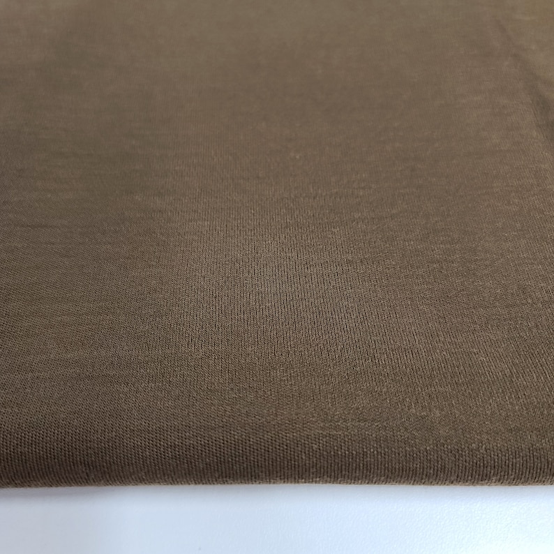 May include: Close-up of a brown fabric with a smooth, textured surface.