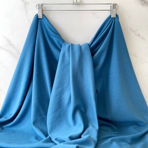 May include: A blue fabric swatch draped over a hanger. The fabric is soft and has a smooth texture.