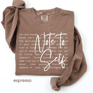 May include: Espresso-colored long-sleeve shirt with the words "Note to Self" in white script. The shirt features a motivational message in white text. The shirt is made of a soft material.