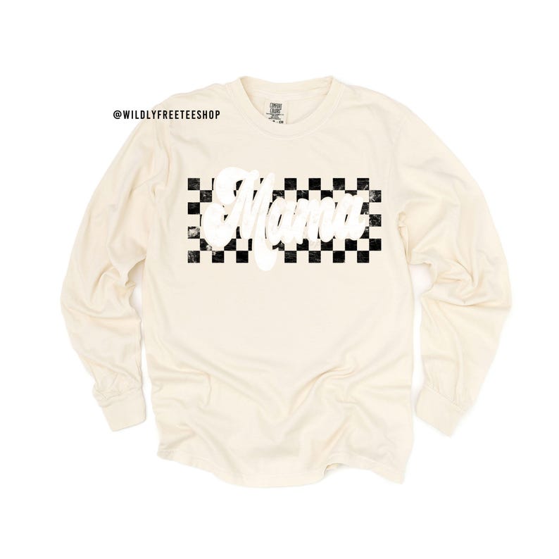 Puede incluir: Una camiseta de manga larga de color crema con un patr&oacute;n de cuadros negros y blancos y la palabra "Mama" en letras blancas.