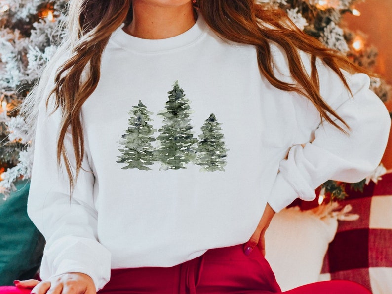 Puede incluir: Sudadera blanca con un dise&ntilde;o de acuarela de tres &aacute;rboles verdes.