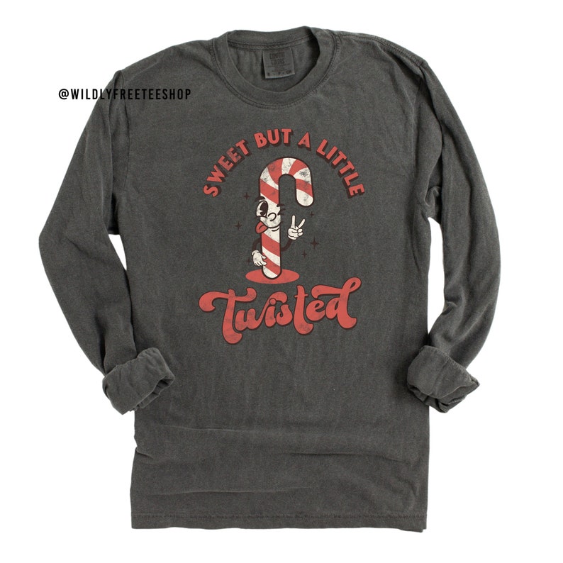 May include: A dark gray long-sleeve t-shirt with a vintage-style graphic of a candy cane with a face and the text "Sweet But A Little Twisted".