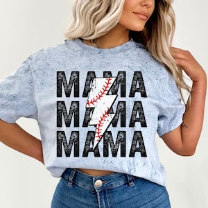 May include: A light blue t-shirt with a distressed look featuring the text "MAMA" repeated three times with a lightning bolt graphic in the centre. The lightning bolt is filled with a baseball graphic.
