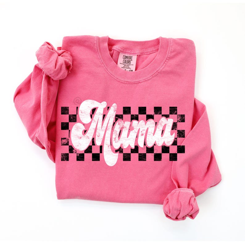 Puede incluir: Camiseta rosa de manga larga con un gr&aacute;fico blanco de "Mama" sobre un fondo a cuadros blanco y negro.