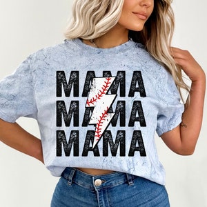 May include: A light blue t-shirt with a distressed look featuring the text "MAMA" repeated three times with a lightning bolt graphic in the centre. The lightning bolt is filled with a baseball graphic.
