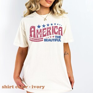 Pu&ograve; includere: Una t-shirt bianca con una grafica in stile vintage che dice "America The Beautiful" in lettere rosse e blu con stelle. La t-shirt &egrave; realizzata in un materiale morbido e confortevole e ha una vestibilit&agrave; rilassata.