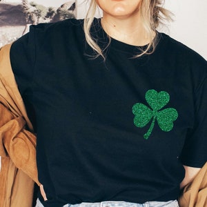 May include: A black t-shirt with a green glitter shamrock design.