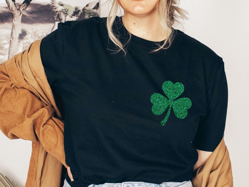 May include: A black t-shirt with a green glitter shamrock design.