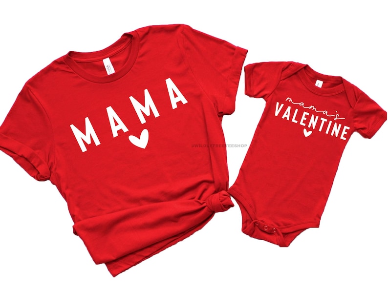 May include: Red t-shirt with the word "MAMA" in white with a small white heart. A red baby onesie with the text "mama's VALENTINE" in white with a small white heart.