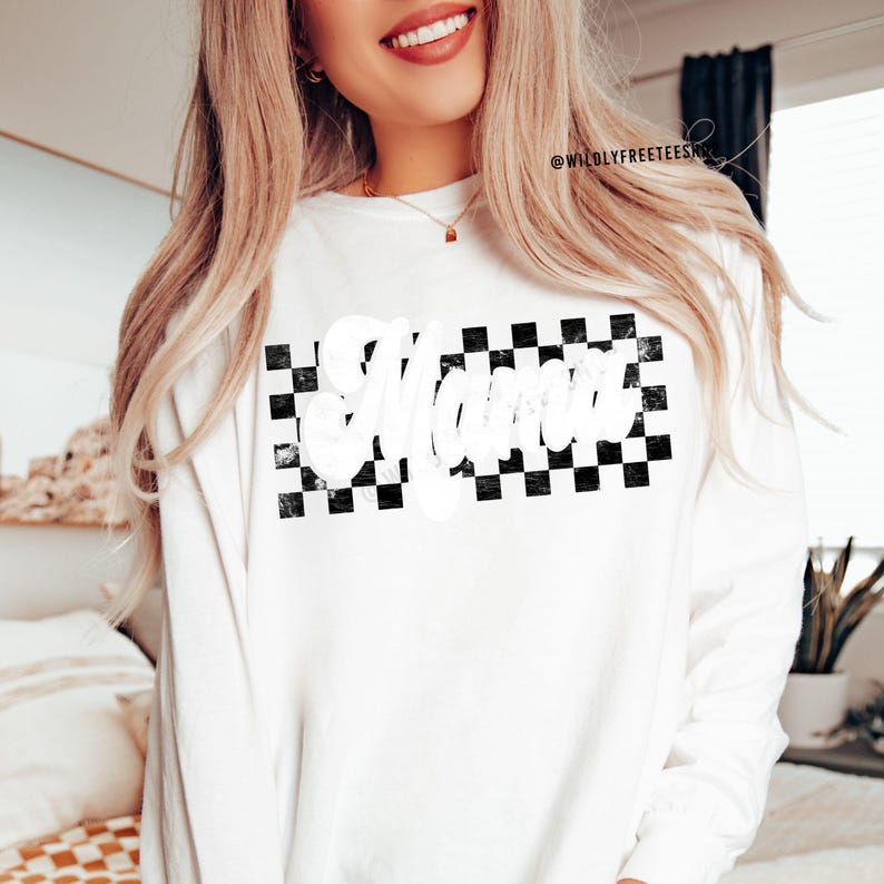 Puede incluir: Camiseta blanca de manga larga con un patr&oacute;n de cuadros blanco y negro y la palabra "Mama" en letras blancas.