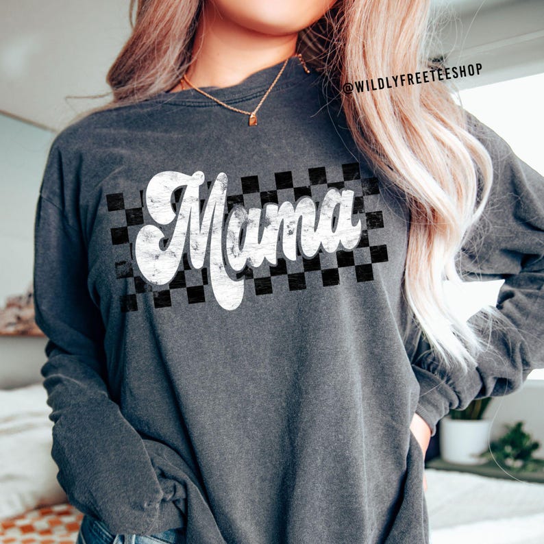 Puede incluir: Una camiseta gris de manga larga con un gr&aacute;fico blanco de estilo vintage "Mama" sobre un fondo a cuadros blanco y negro.