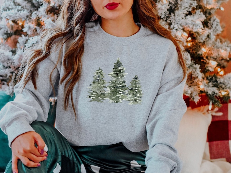 Puede incluir: Una sudadera gris con un dise&ntilde;o de acuarela de tres &aacute;rboles verdes. Los &aacute;rboles est&aacute;n dispuestos en forma de tri&aacute;ngulo.