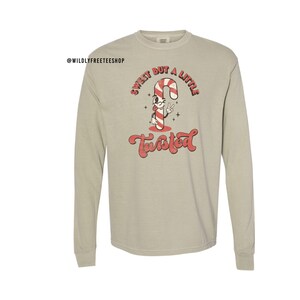 May include: A light gray long-sleeve t-shirt with a red and white candy cane graphic and the text "Sweet but a little Twisted".