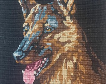 May include: A detailed tapestry depicting a German Shepherd dog's head and shoulders. The dog's fur is rendered in shades of brown, tan, and blue, with a pink tongue. The background is solid black.