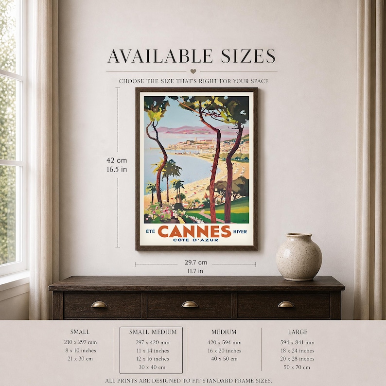 May include: Framed vintage travel poster for Cannes, France, featuring a coastal landscape with palm trees and the text "Cannes Cote D'Azur." The poster is 16.5 inches tall and 11.7 inches wide. Available sizes are listed below the poster.
