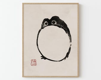 May include: Black and white ink illustration of a round, cartoon-like creature with large eyes. The creature is surrounded by a circle, and the image is framed in a light wood frame. A red stamp with Japanese characters is in the bottom left corner.