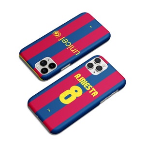 May include: Two phone cases with a blue and red striped design. One case features the word "unicef" in yellow, and the other displays "A.INIESTA 8" in yellow. The cases have a glossy finish and are set against a white background.