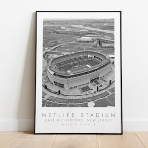Könnte beinhalten: Schwarz-Weiß-Luftaufnahme des MetLife Stadium in East Rutherford, New Jersey. Das Stadion ist der Mittelpunkt, mit umliegender Infrastruktur und der Skyline der Stadt im Hintergrund. Der Text "METLIFE STADIUM" ist unter dem Bild gedruckt.