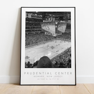 May include: Black and white photograph of a hockey game at the Prudential Center in Newark, New Jersey. The photo shows the ice rink from the upper level of the arena, with fans in the stands.