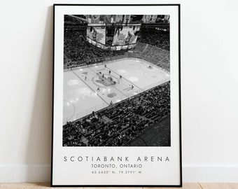 May include: Black and white photograph of Scotiabank Arena in Toronto, Ontario. The image shows the ice hockey rink from above, with players on the ice and fans in the stands. The text "Scotiabank Arena" and "Toronto, Ontario" is printed below the image, along with the coordinates "43.6435° N, 79.3791° W".