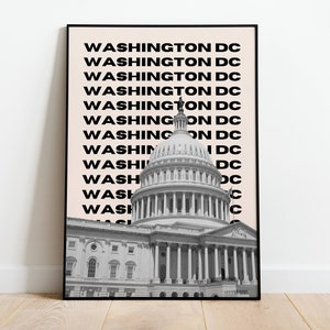 May include: A black and white photograph of the United States Capitol building in Washington, D.C. The image is framed in a black frame and has a light pink background with the text "WASHINGTON DC" repeated multiple times.