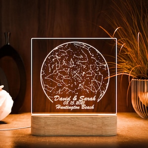 May include: A white LED night light with a wooden base. The light features a constellation map with the text "David & Sarah 08.15.2021 Huntington Beach".