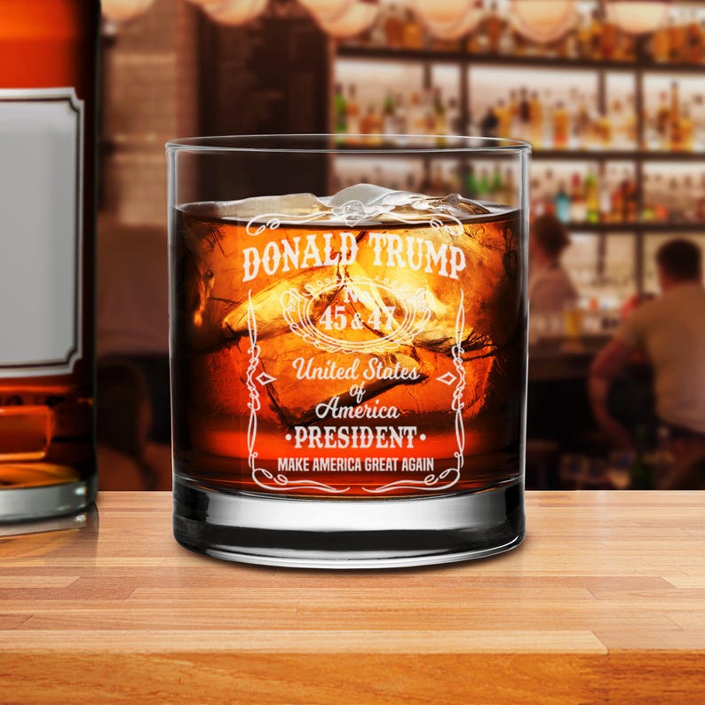 Puede incluir: Un vaso de vidrio transparente con un dise&ntilde;o blanco que dice "DONALD TRUMP 45 & 47 Estados Unidos de Am&eacute;rica &bull;PRESIDENTE. HAGA QUE AM&Eacute;RICA SEA GRANDE OTRA VEZ".