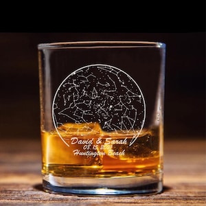 May include: A clear glass rocks glass with a design etched into the side. The design is a circle with stars and constellations inside. The text "David & Sarah 08.15.2021 Huntington Beach" is etched below the circle.