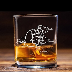 May include: A clear glass with a design of five fists holding each other, with the names "Daddy", "Emma", "Hannah", and "Charlie" etched on the glass. The glass is filled with amber liquid and ice cubes.