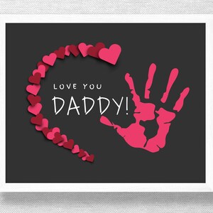 May include: A black and white printable card with a pink handprint and a heart made of pink hearts. The text "Love you Daddy!" is written in white.