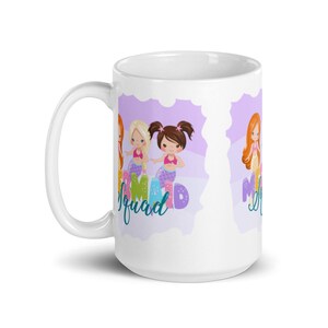 Puede incluir: Taza de cer&aacute;mica blanca con fondo morado y tres sirenas de dibujos animados. El texto "Mermaid Squad" est&aacute; escrito en la taza.