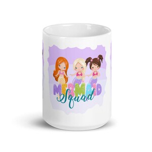 Puede incluir: Taza de cer&aacute;mica blanca con un dise&ntilde;o morado y blanco con tres sirenas de dibujos animados con el texto "Mermaid Squad".