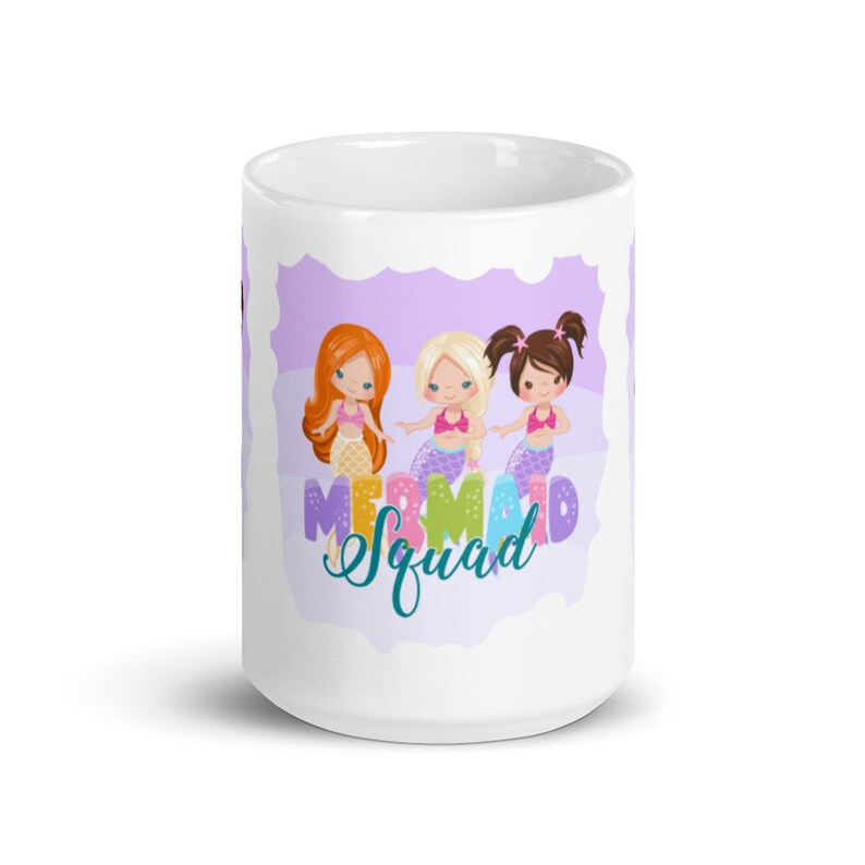 Puede incluir: Taza de cer&aacute;mica blanca con un dise&ntilde;o morado y blanco con tres sirenas de dibujos animados con el texto "Mermaid Squad".