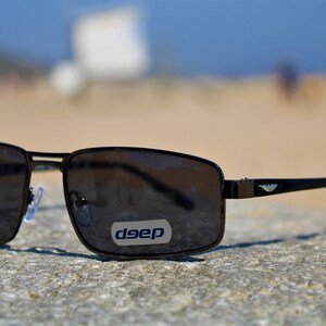 May include: Black rectangular sunglasses with a silver logo that says "deep" on the right lens.