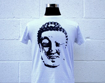 May include: White t-shirt with a black and white graphic print of a Buddha's face.