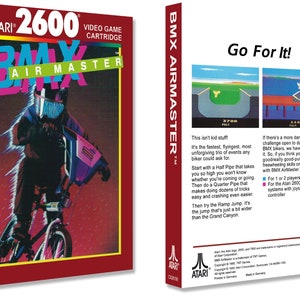 Può includere: Una scatola di cartuccia di gioco Atari 2600 rossa e bianca con il logo BMX Air Master e un'immagine di una persona che guida una BMX rosa. Il retro della scatola contiene una descrizione del gioco e le istruzioni per giocare.