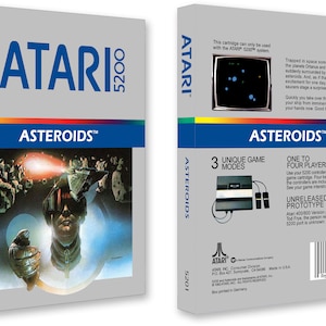 Könnte beinhalten: Eine Vintage-Atari-5200-Spielkassette für Asteroids. Die Vorderseite der Schachtel zeigt eine futuristische Illustration eines Raumschiffs und eines Piloten. Die Rückseite der Schachtel enthält Spieldetails, darunter drei einzigartige Spielmodi und ein bis vier Spieler. Die Schachtel ist grau mit blauen Akzenten.