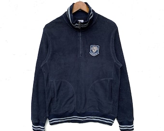 May include: A black fleece pullover with a half-zip closure and a New York Yankees logo patch on the chest. The pullover has a ribbed collar, cuffs, and hem.