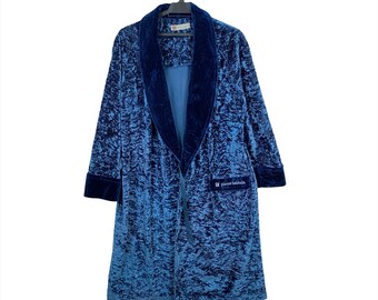 May include: A blue velvet robe with a wide, dark blue velvet collar and a pocket on the right side. The robe has a Pierre Balmain label on the pocket.