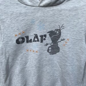 May include: Gray hooded sweatshirt with a black and white graphic of Olaf from Frozen. The graphic says "Olaf" with a series of "x" symbols around it.