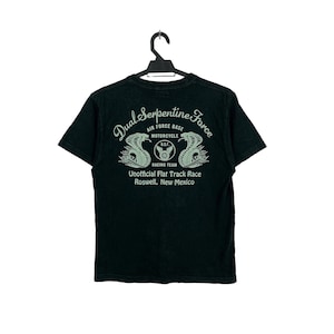 May include: Black t-shirt with a green graphic print of two snakes with the text "Dual Serpentine Force", "Air Force Base", "Motorcycle", "D.S.F. Racing Team", "Unofficial Flat Track Race", and "Roswell, New Mexico".