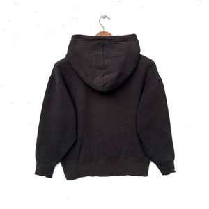May include: A black hooded sweatshirt with a drawstring hood. The sweatshirt is hanging on a wooden hanger against a white background.
