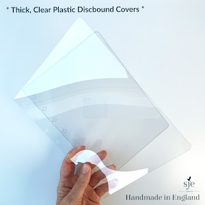 May include: Three clear plastic discbound covers stacked on top of each other. The covers are thick and translucent, allowing the contents of a binder to be seen through them. *Thick, Clear Plastic Discbound Covers*