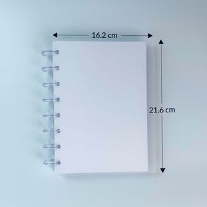 May include: A white notebook with a clear plastic spiral binding. The notebook measures 16.2 cm by 21.6 cm.