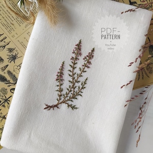 Könnte beinhalten: Ein weißes Leinentuch mit einer gestickten Heidekraut-Zweig in Grün- und Lilatönen. Der Text "PDF - PATTERN + YouTube video" ist sichtbar. Getrocknete Pflanzen und Vintage-Papier bilden den Hintergrund.