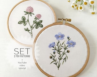 May include: Two embroidery hoop sets with floral designs. The first hoop features a clover with pink flowers and green leaves. The second hoop features a blue flax flower with green leaves. The text "SET 2 PDF-PATTERNS + YouTube video tutorial" is below the hoops.