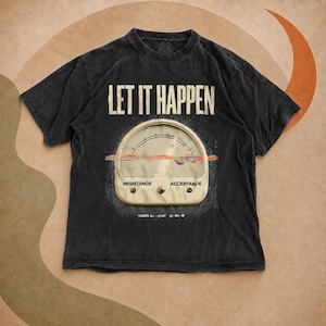 Puede incluir: Una camiseta de manga corta en color negro carbón con el texto LET IT HAPPEN en letras mayúsculas blancas. Debajo del texto hay un gráfico de un medidor analógico con las palabras RESISTANCE y ACCEPTANCE, y una línea horizontal multicolor.
